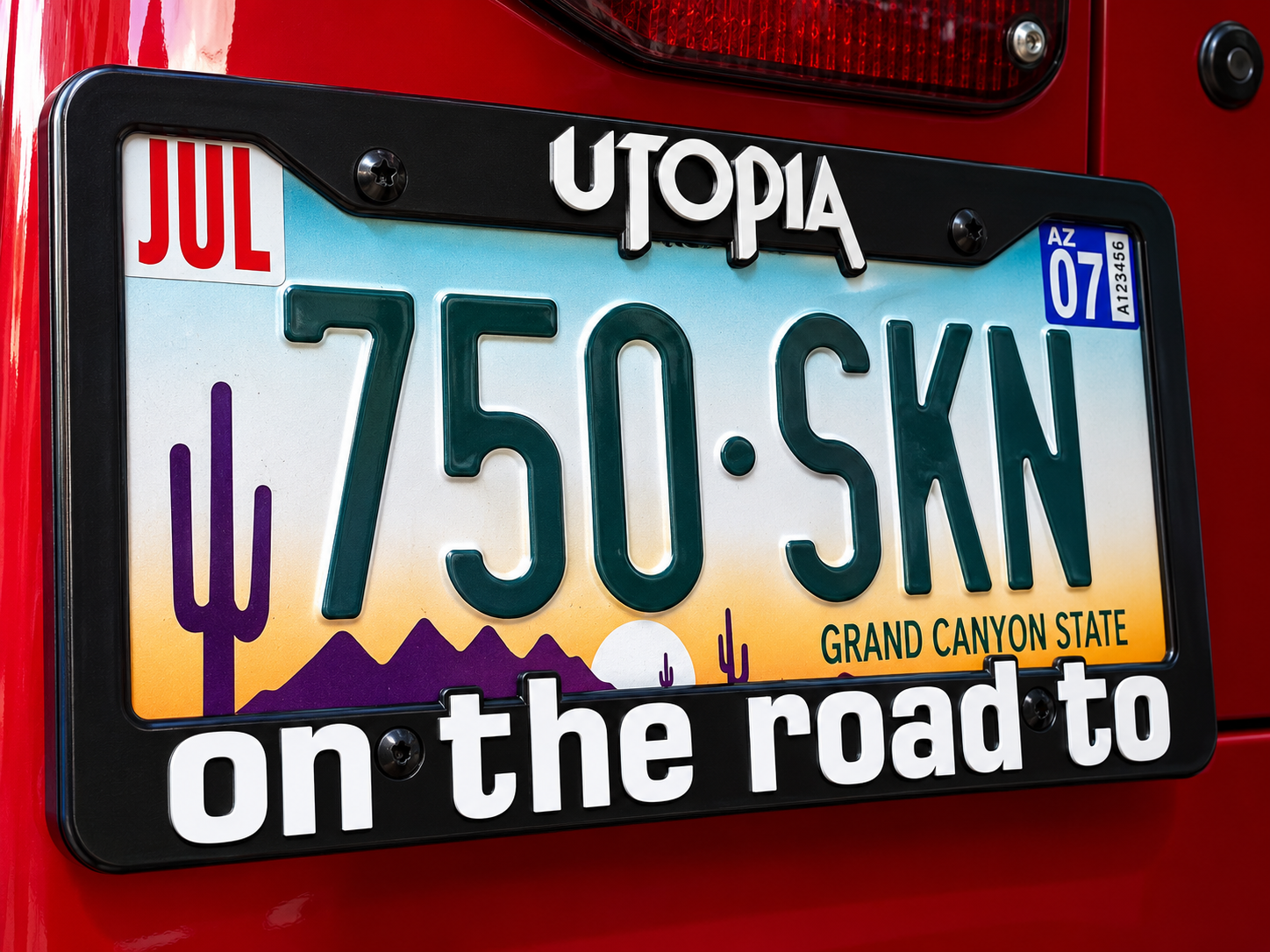 Utopia on the road to license plate frame installed on a red vehicle